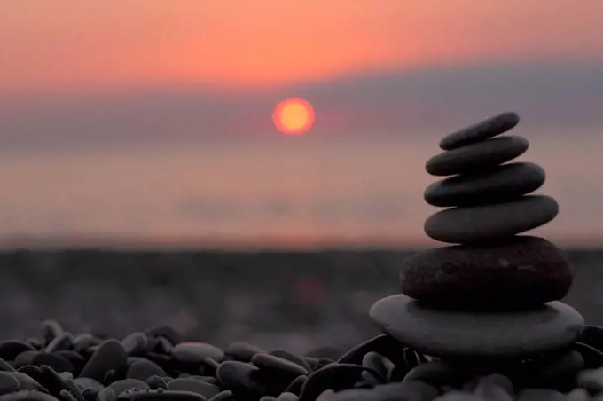 cairn on the beach in front of the rising sun