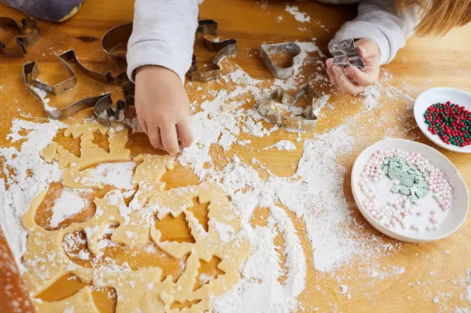Girl baking christmas cookies, hands, detail, dough, sugar pearls, decorate