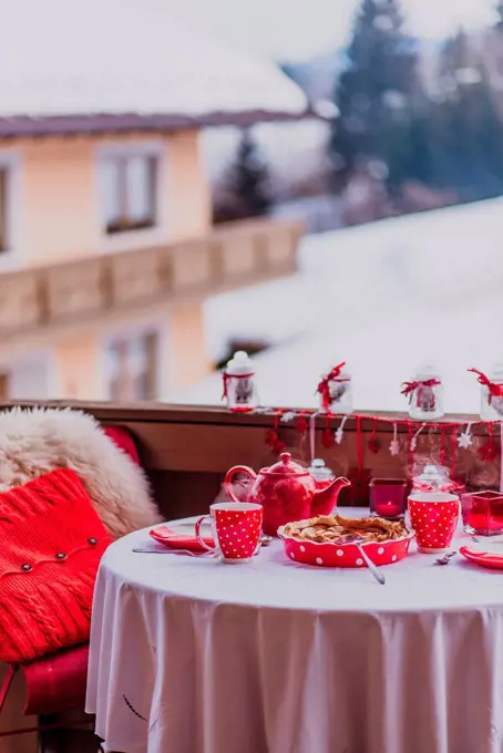 table laid in red on a balcony in winter