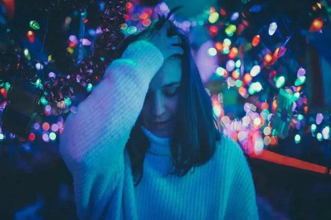 brunette woman moving her hair between Christmas lights