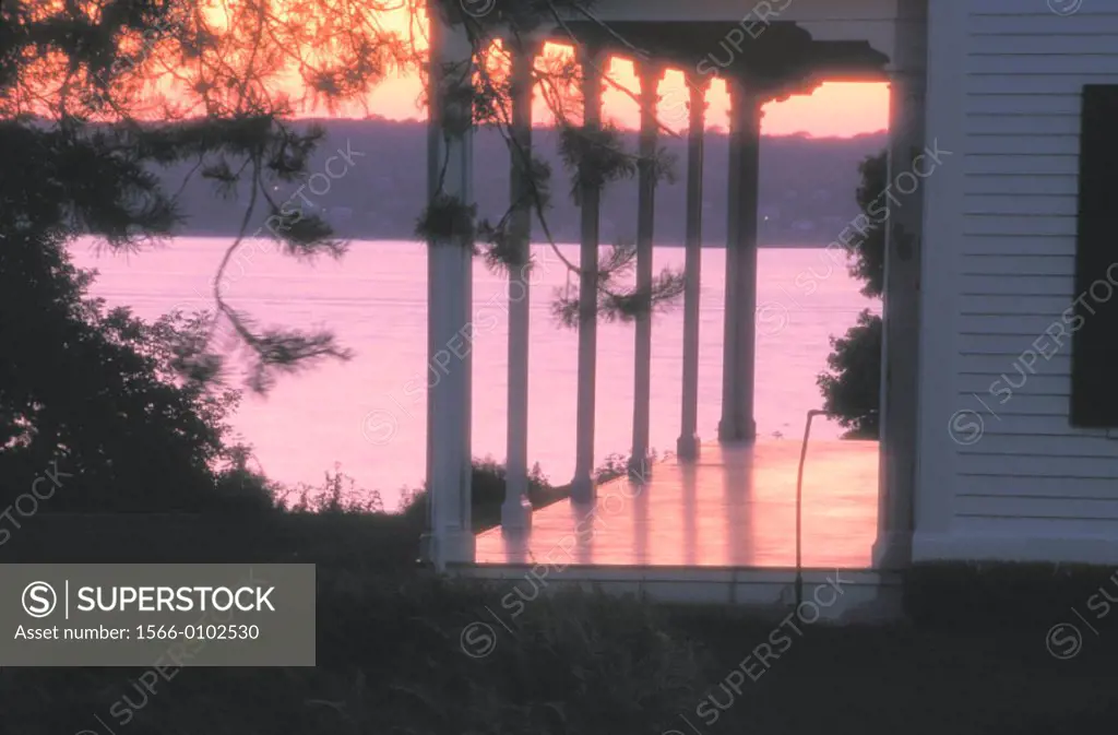 Porch of a New England style wood frame house backlit at sunset with river in the background in Rhode Island, USA