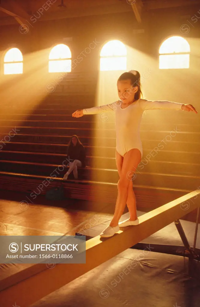 Young girl practicing on balance beam.
