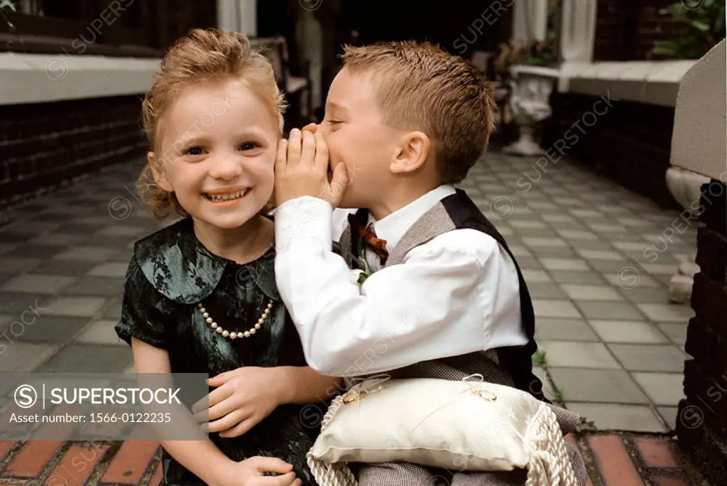 Children whisper to each other as they prepare to be ring bearers at a wedding