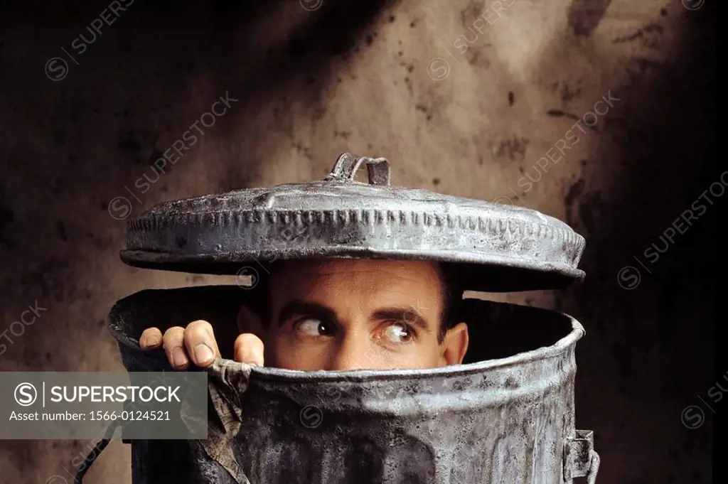 Man peering out of trash can