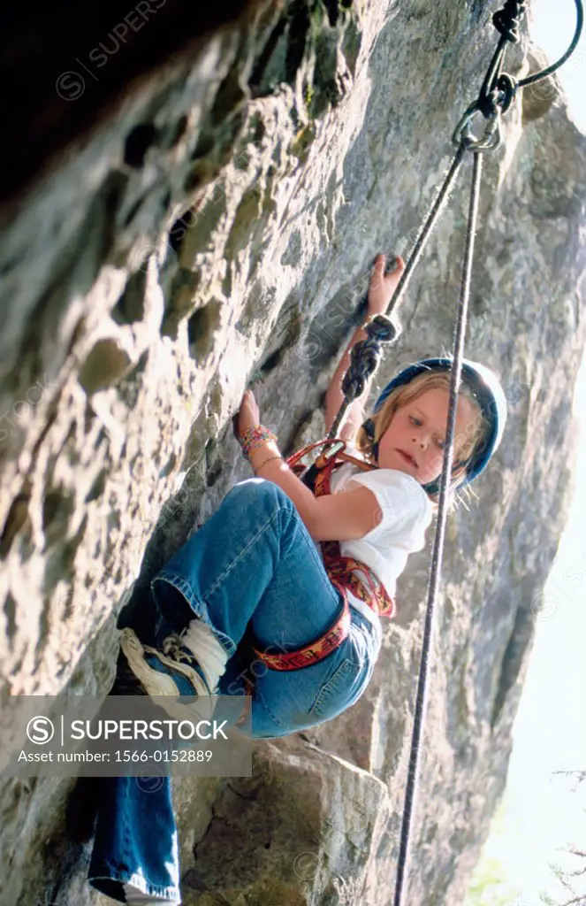 Young girl climbing rock face at rock climbing school