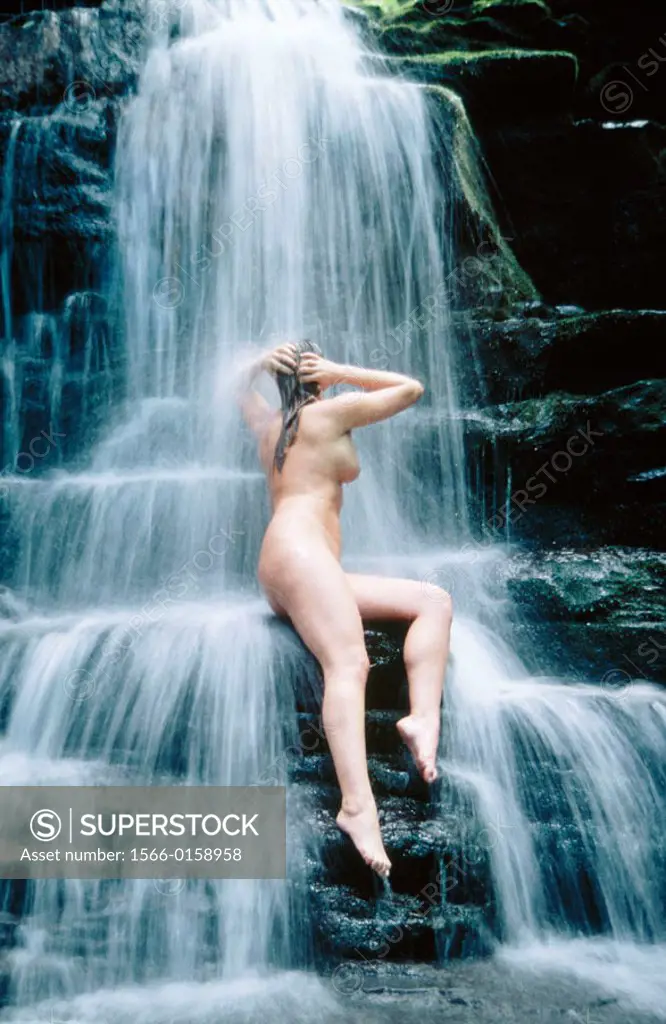 Woman bathing in waterfall