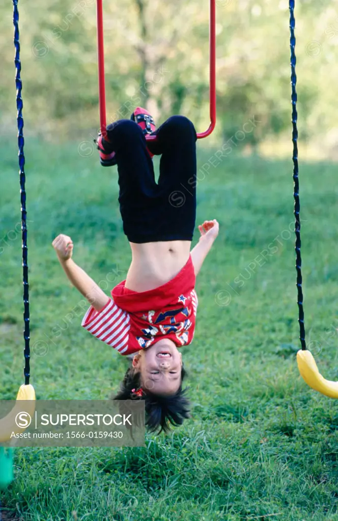 Girl hanging upside down on playset