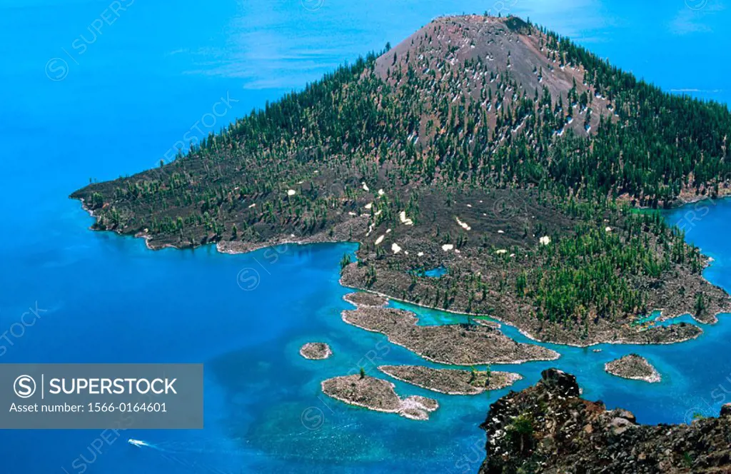 A tour boat cruises past Wizard Island on Crater Lake. Crater Lake National Park. Oregon. USA