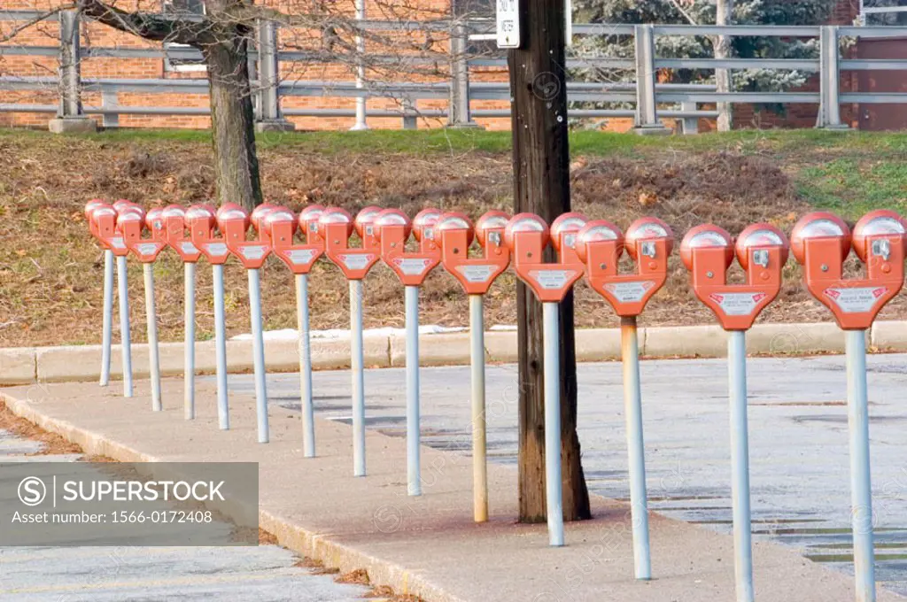 Row of automobile parking meters in public parking lot