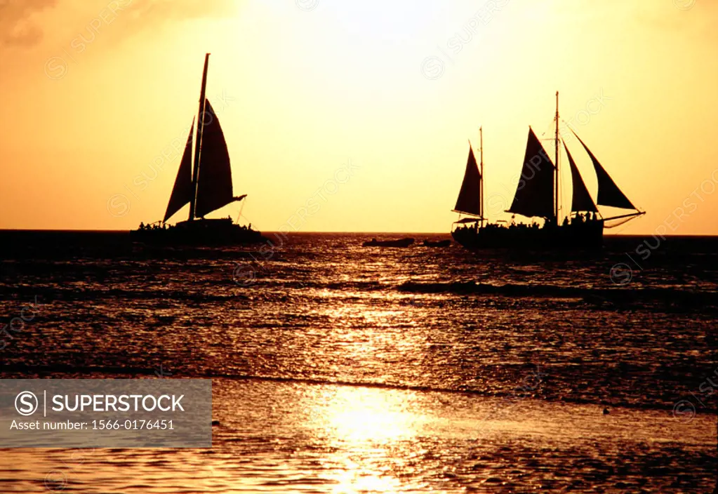 Sailboats at sunset crossing wakes in Aruba. Dutch Antilles.