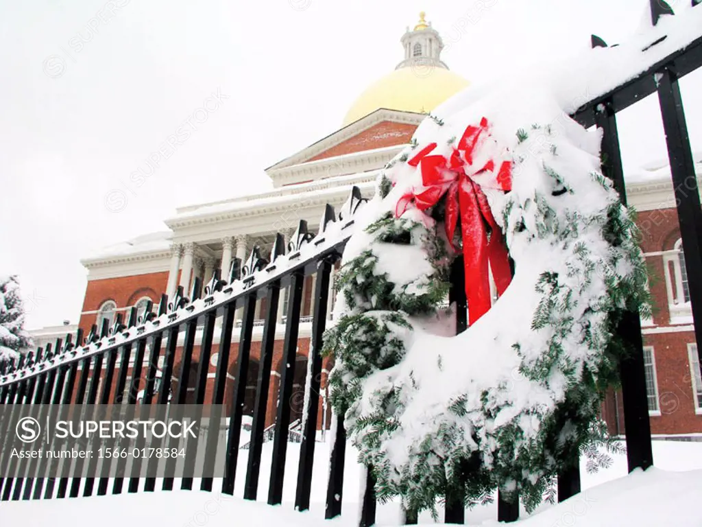 Boston, MA: Snow covers the lawn of the Massachusetts State House while a Christmas wreath decorates an iron fence in front.