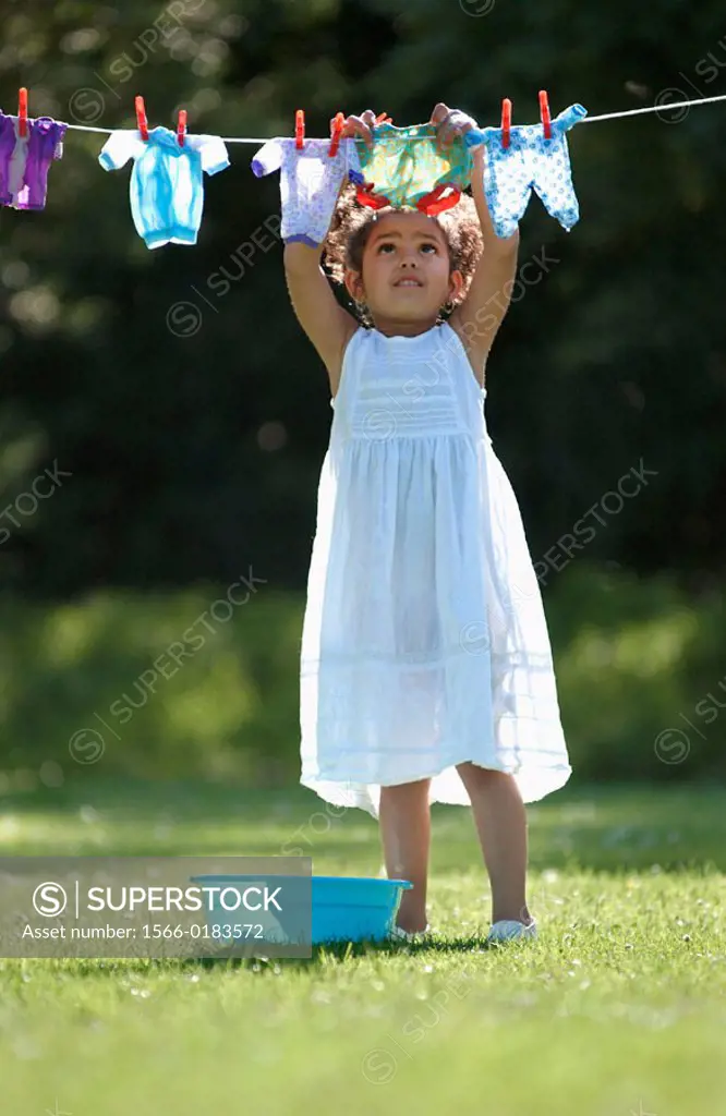 Girl hanging her doll´s clothes