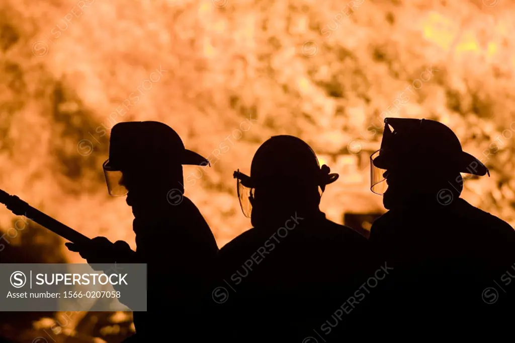 Firemen in silhouette. Rockport fourth of July holiday bonfire. Rockport. Massachusetts. USA.