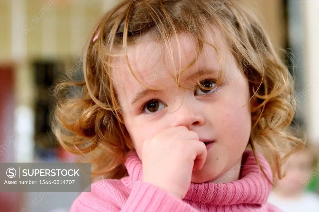 Three year old girl , looking very pensive and worried, at nursrey school