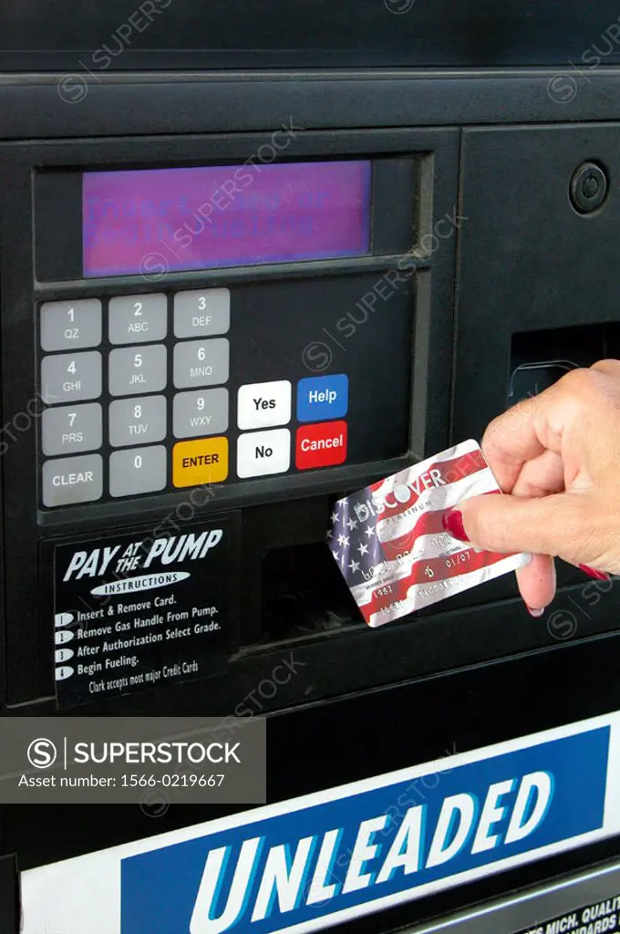 Woman pays at the gas pump with a Discover card.