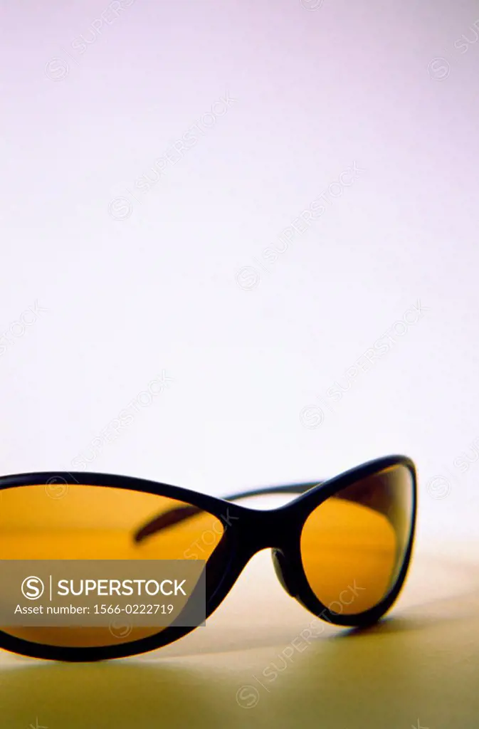 Funky plastic black rimmed wraparound sunglasses with brown/orange glass on graduated background.