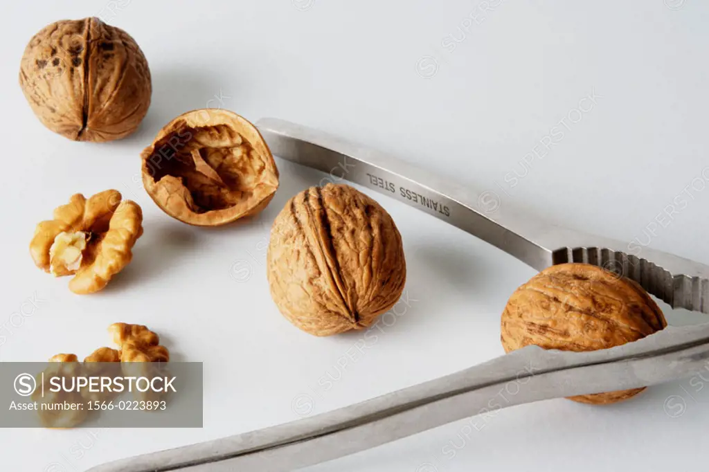 Three closed nuts and one open with metallic nutcracker