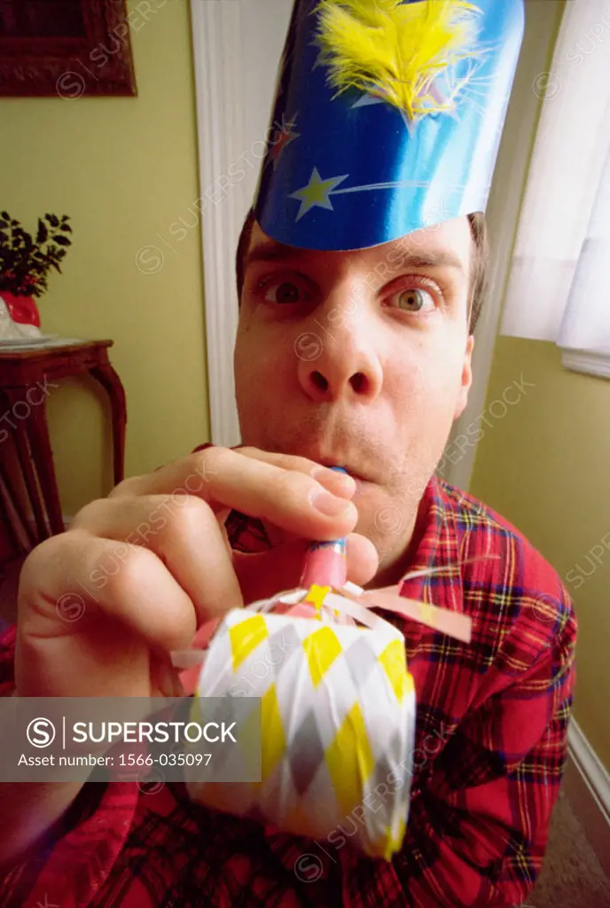Man in pajamas with party hat and party blower