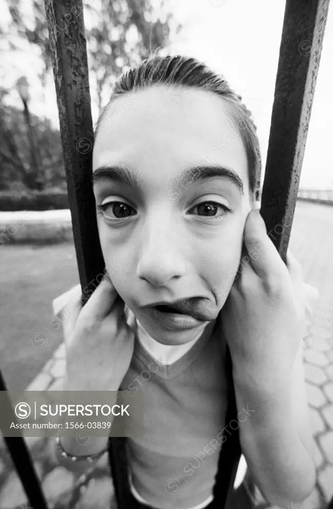 Young girl´s face caught in bars