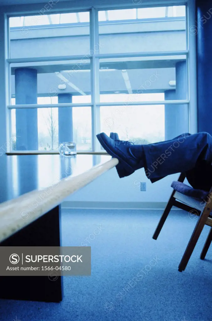 Businessman relaxing with feet up on table (toned blue)