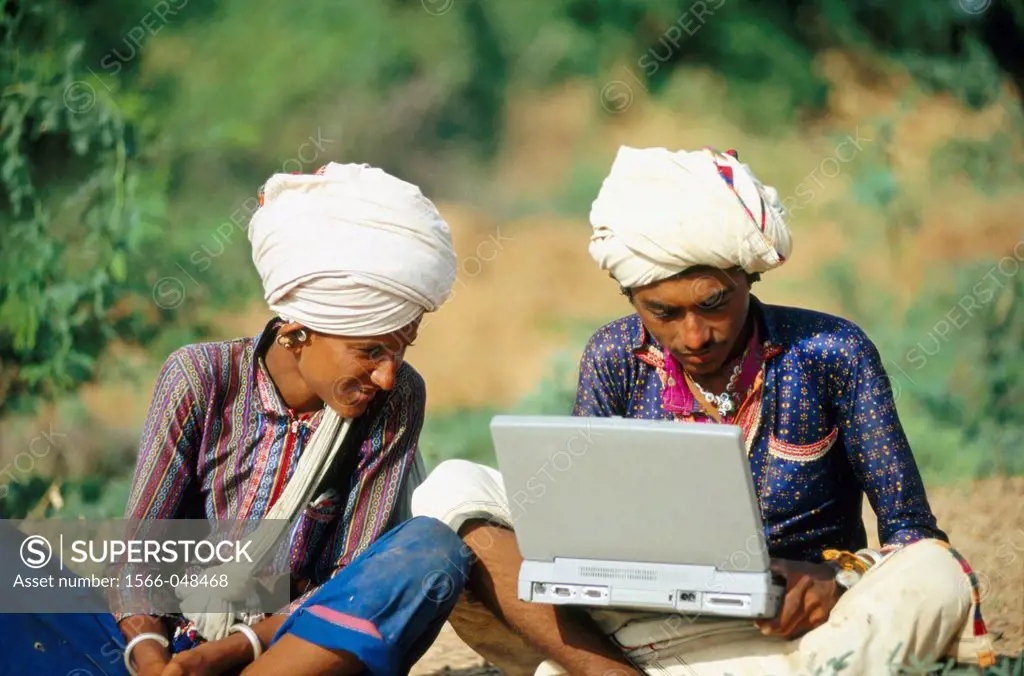Two rural Indians with white turbans working on a laptop in Kutch, Gujarat, India.