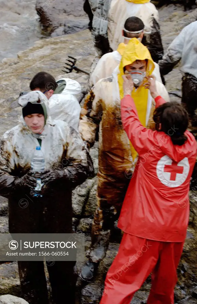 Volunteers dressed with protective clothing gathering the fuel spill (´chapapote´) of Prestige tanker. Dec. 2002. Galicia. Spain