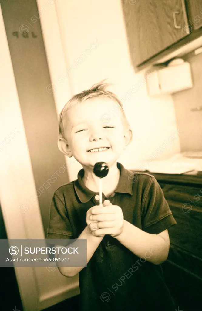 Three year old boy holds tootsie pop (sepia tone)