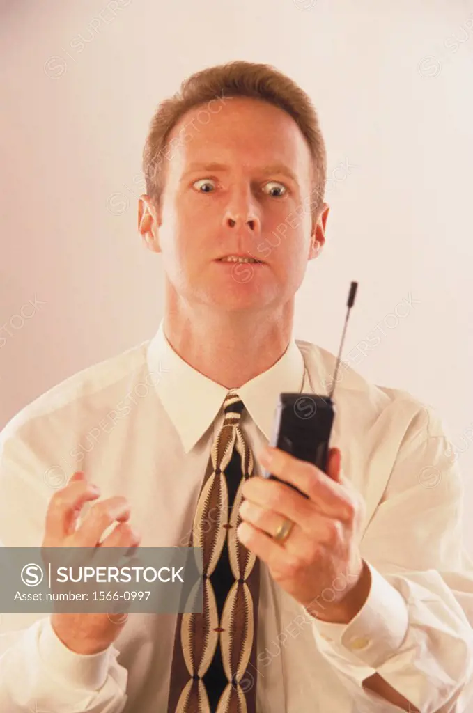 Businessman with cell phone suffering a nervous breakdown