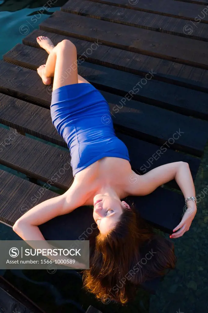 Spread on a wooden pier young woman