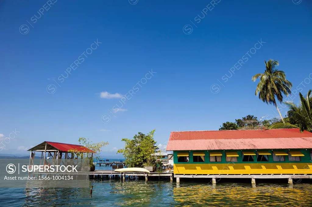 Brightly colored wooden houses sit over the sea in the historic town of Old Bank on Isla Bastimentos, Bocas del Toro, Panama