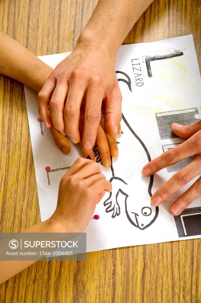 A teacher guides a blind child´s hands over the outline of a lizard in raised type in a special needs writing class at the Blind Children´s Learning C...