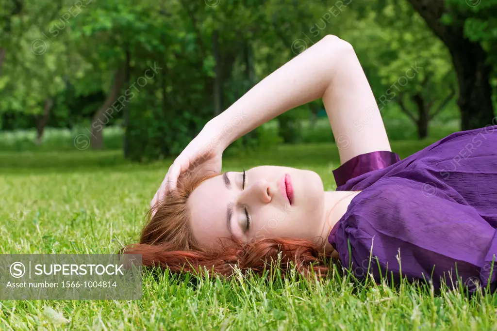 Young woman with closed eyes lying on the grass in a park
