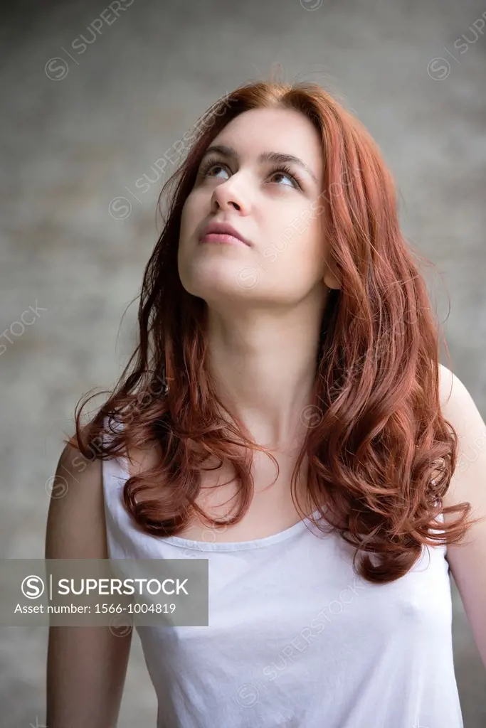 Portrait of a pensive young woman with red hair looking up