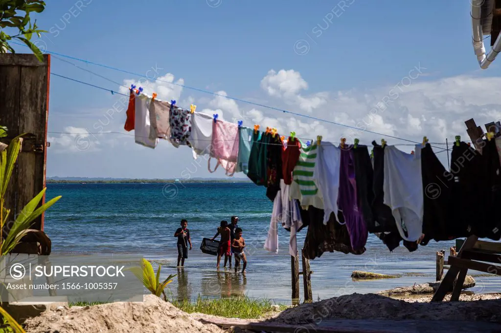 Children wading in the ocean with laundry drying in the foreground on Isla Carenero, Bocas del Toro, Panama