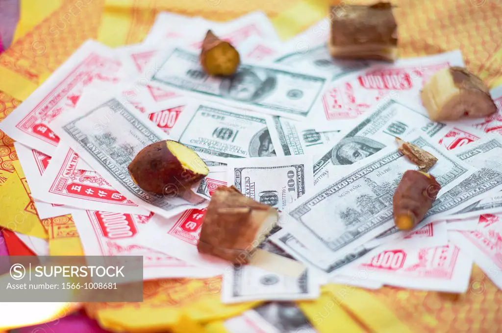 Fake money offerings with weights holding them down at a temple in Vietnam