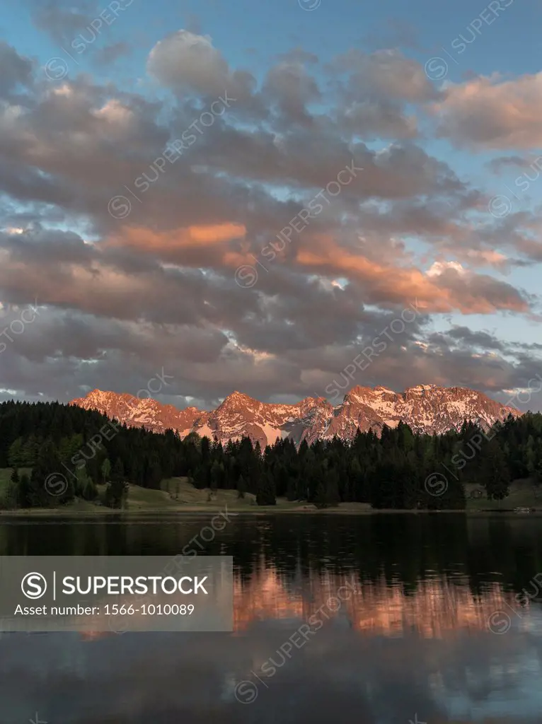 The Karwendel Mountain Range near Mittenwald during spring, lake Wagenbruch also called Geroldsee Sunset over the lake with the still snow covered pea...