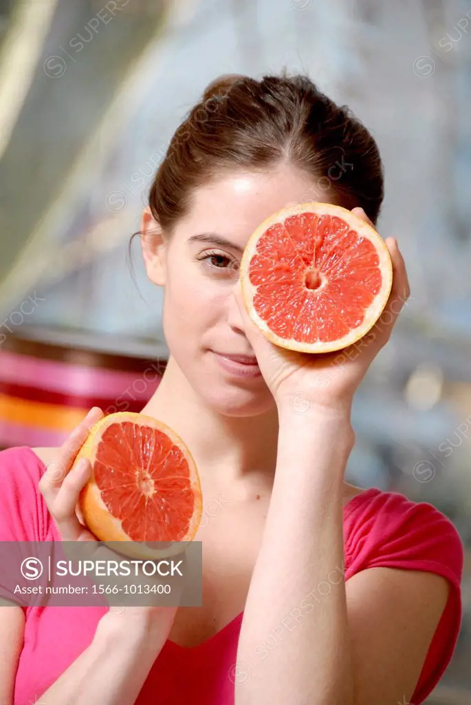 Woman holding fruit  Young woman holding half a pink grapefruit in both hands