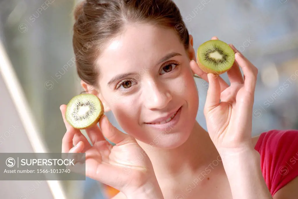 Woman holding fruit  Young woman holding half a kiwi in both hands
