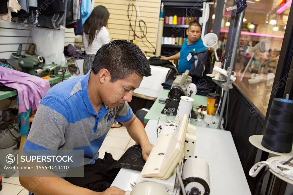 Los Angeles, California - A man sews clothing at a tailor shop in the Los Angeles Fasion District