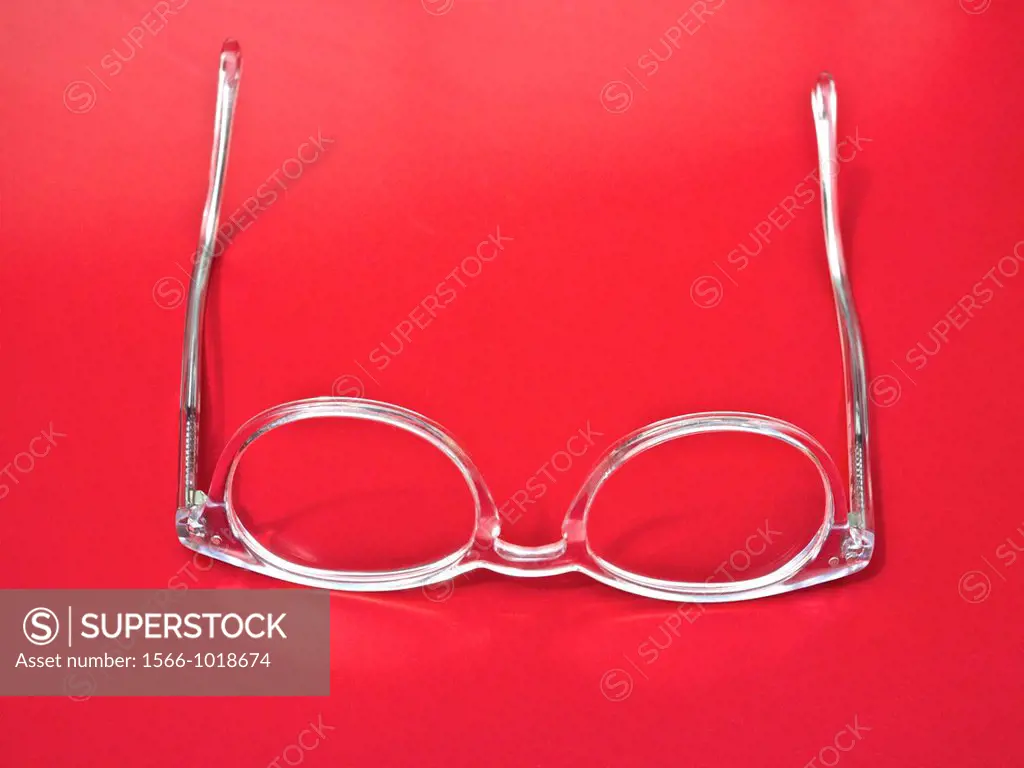 Fashionable transparent pair of glasses on a red bakground