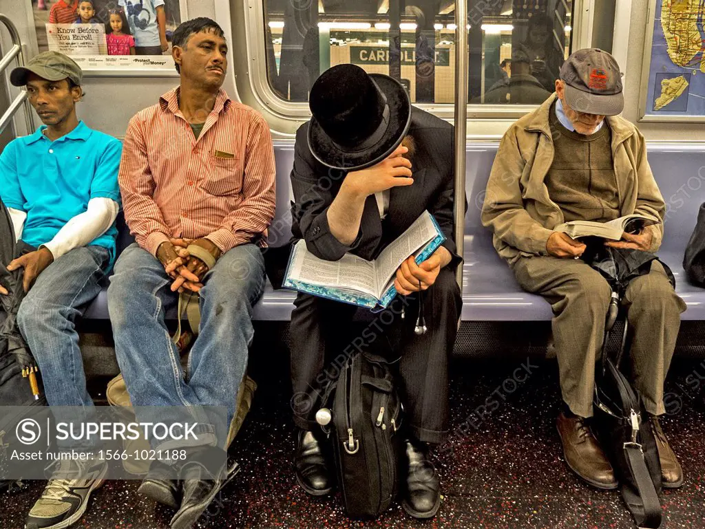 An Orthodox Jew reads a book in Hebrew while an elderly man reads a paperback and two Hispanic laborers just seem to be bored on the subway in New Yor...