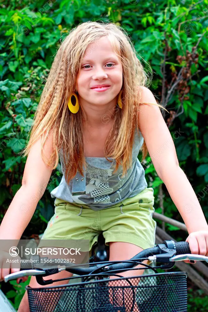 A 12 years old girl sitting on the bike in the garden