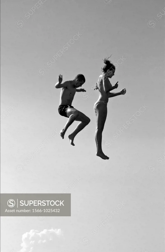 young couple jumping from the jumping tower to water, beach on the Geneva Lake in Geneva called ´Paquis plage´, Geneva, Switzerland
