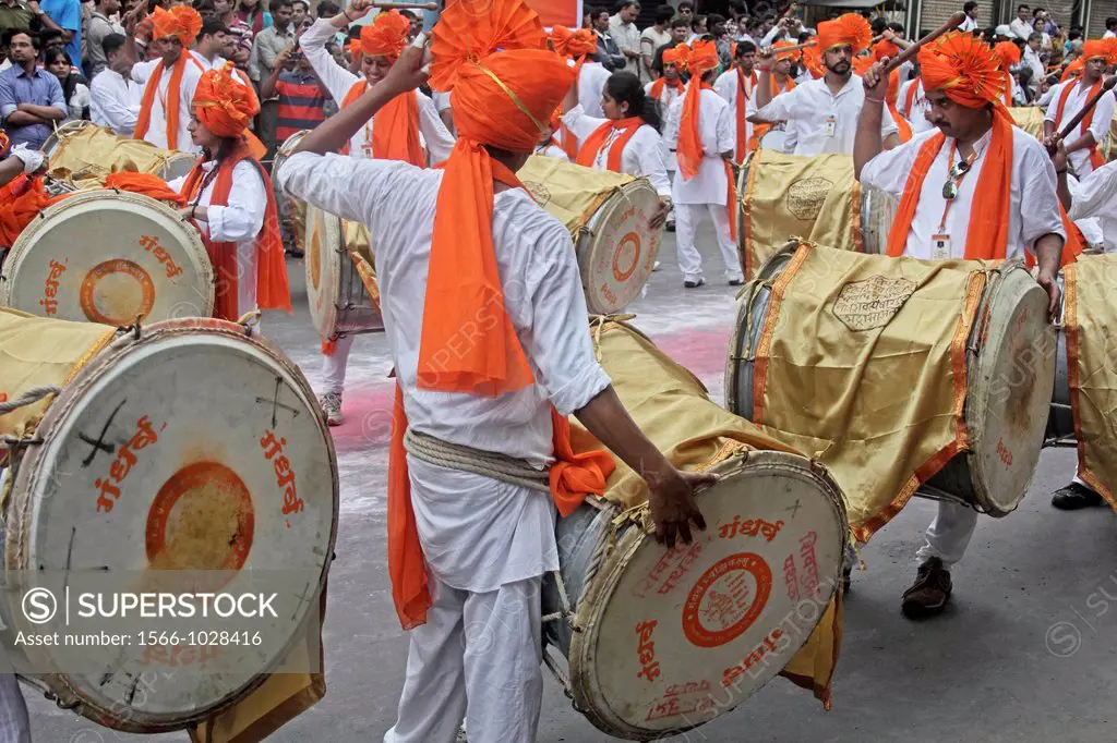 Indian girls & men wearing headgear called feta and white kurta pajamas and playing musical instrument called ´dhol-taash´ during Anant Chaturdashi Ga...