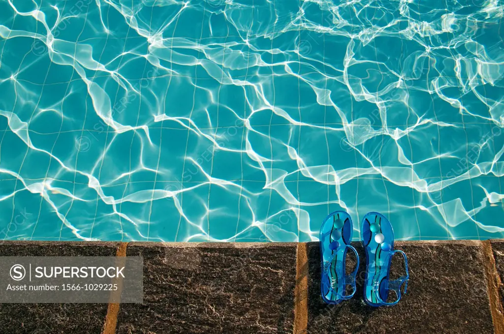swimming pool in summer, no people, woman´s sandals at poolside