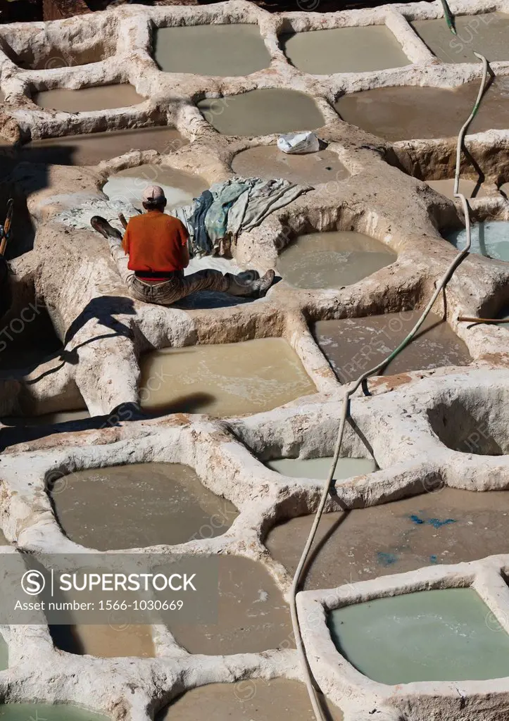 worker in the thousand year old leather tannery in the ancient medina of Fes, Morocco