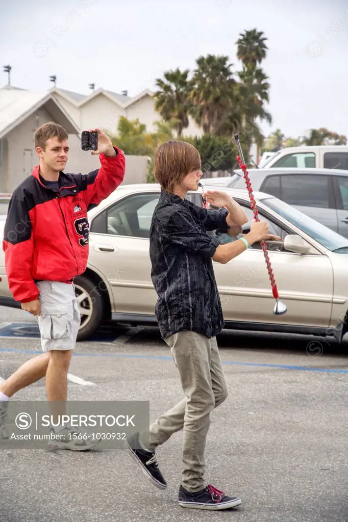A teenage drum major practices marching with his baton while a friends makes a video in a San Clemente, CA, high school parking lot  The drum major is...