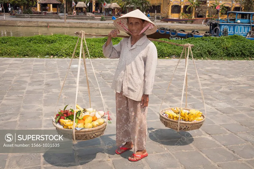 A Vietnamese woman, carrying baskets of fruit, Hoi An, Quang Nam province, Vietnam