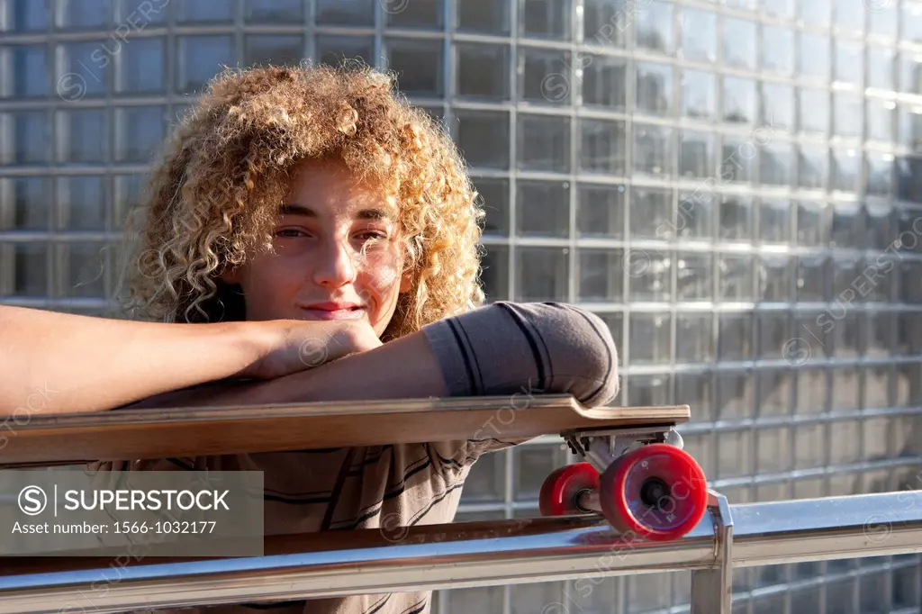 Teenage boy leaning on his skateboard