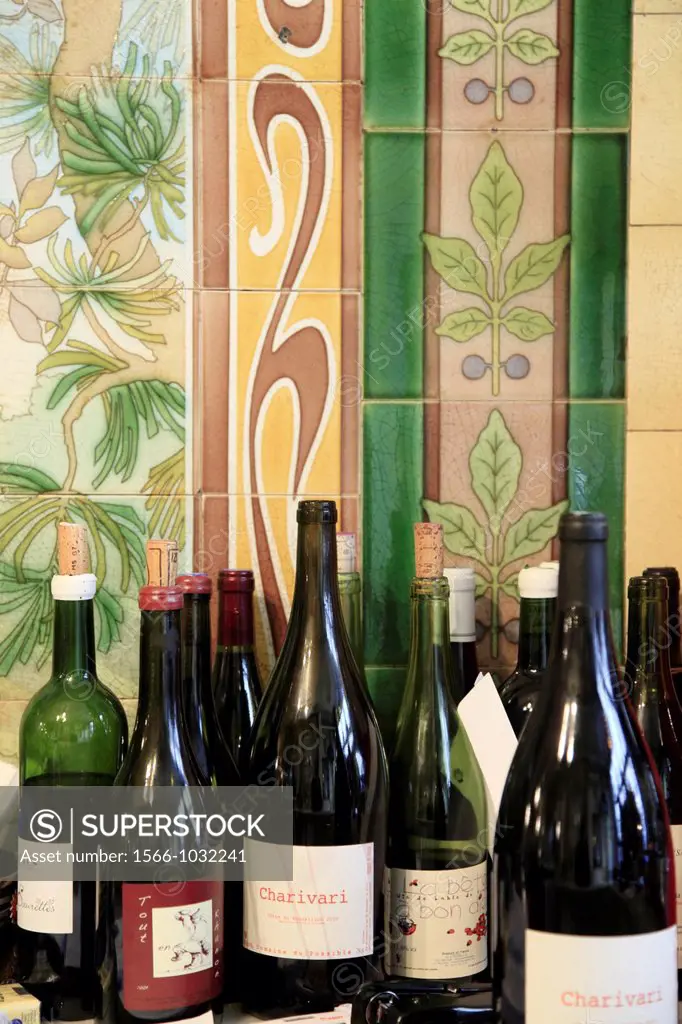 Art Nouveau style tiles decorations from a previous exotic bird shop in restaurant Vivan with bottles of organic wine in foreground  Paris  France.